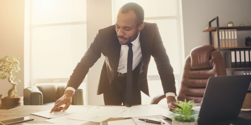 6-signs-its-time-to-grow-your-law-firm Male attorney reviewing documents at a desk deciding whether to grow law firm