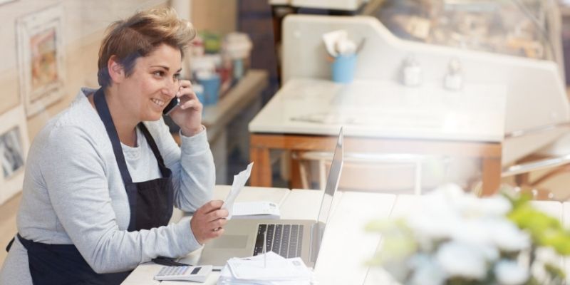 small-business-taxes-2020-covid-19-federal-tax-relief Female business owner on the phone while preparing 2020 business tax filing