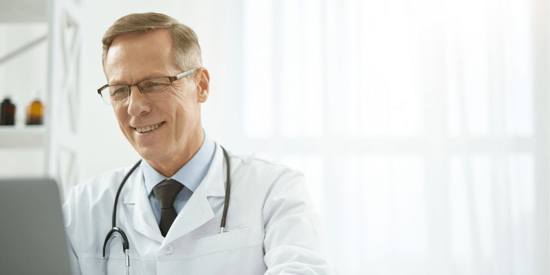 medical-practice-growth-strategies-how-to-attract-patients-new-clinic caucasian male doctor sitting at desk working on computer